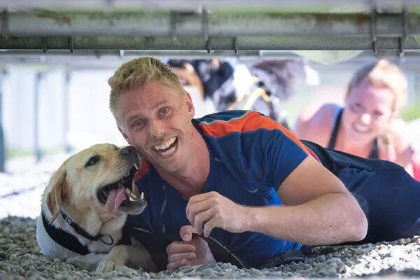Mann und Labrador liegen lachend auf der nassen Rutschbahn